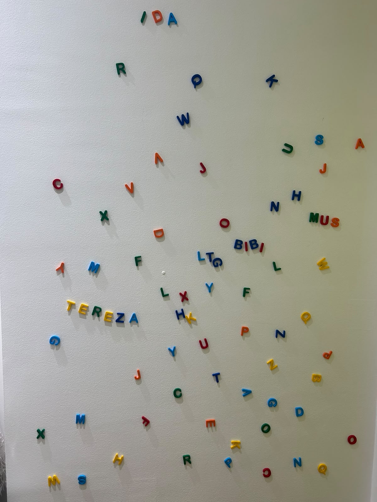 Parede branca de pinos com peças coloridas numa sala do IDA